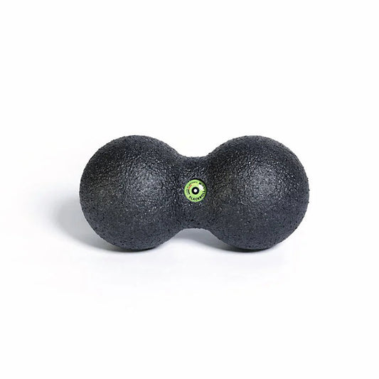 Black massage ball with a green dot on a white background