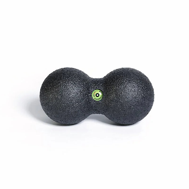 Black massage ball with a green dot on a white background