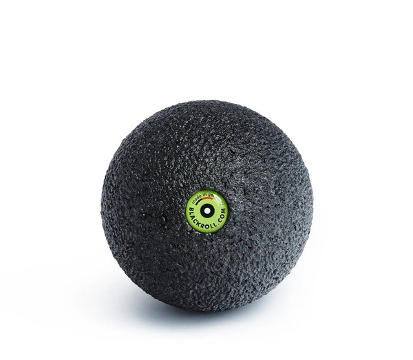 Black massage ball with a green label on a white background