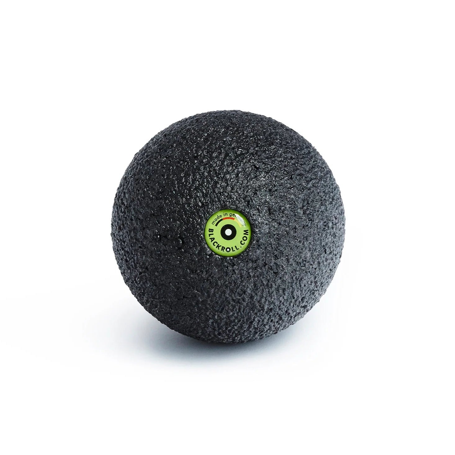 Black massage ball with a green label on a white background