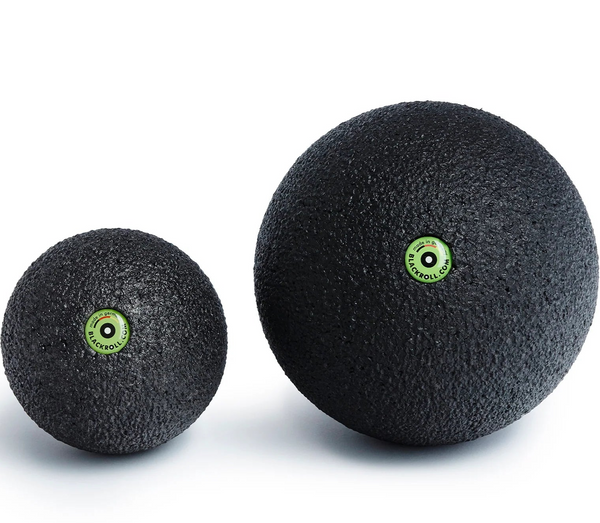 Two black massage balls with green logos on a white background