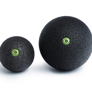 Two black massage balls with green logos on a white background