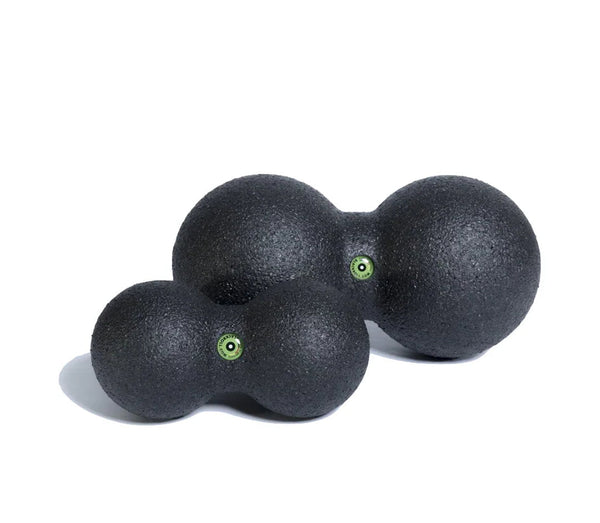 Two black massage balls with green accents on a white background